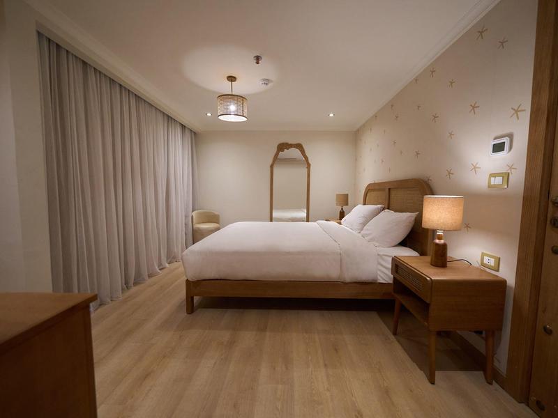 Nowoczesny pokój hotelowy z łóżkiem podwójnym, drewnianymi meblami i miękkim oświetleniem.