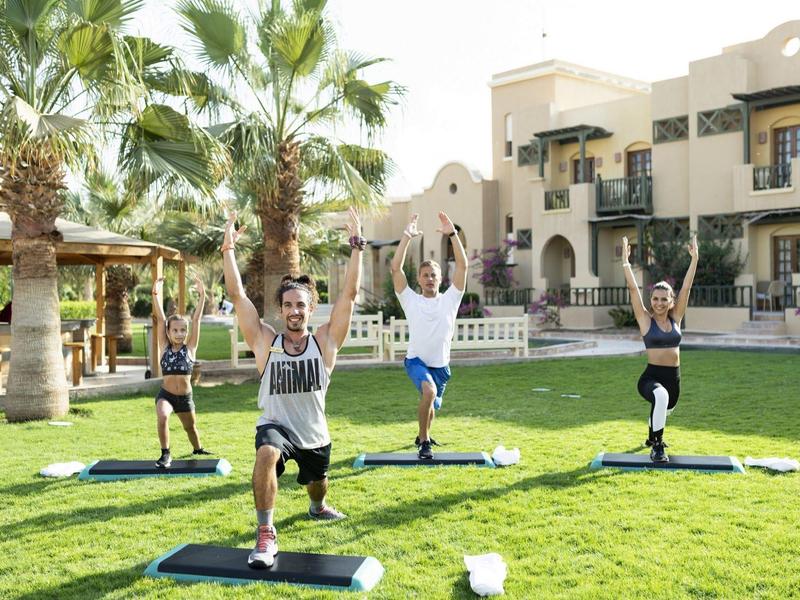 Gruppo fa yoga sull'erba davanti all'hotel con sole.