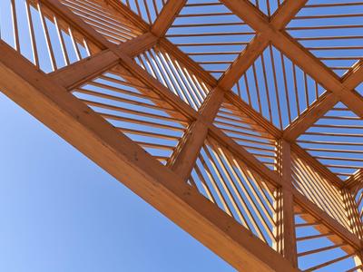 Struttura in legno con stecche inclinate sotto un cielo azzurro.