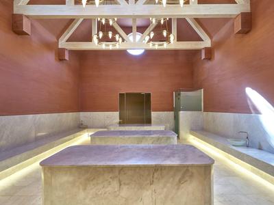 Interno moderno con pareti rosse, tavoli in marmo e lampade sospese.