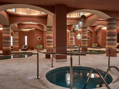 Spa elegante con vasche rotonde, colonne decorative e pareti dai toni caldi.