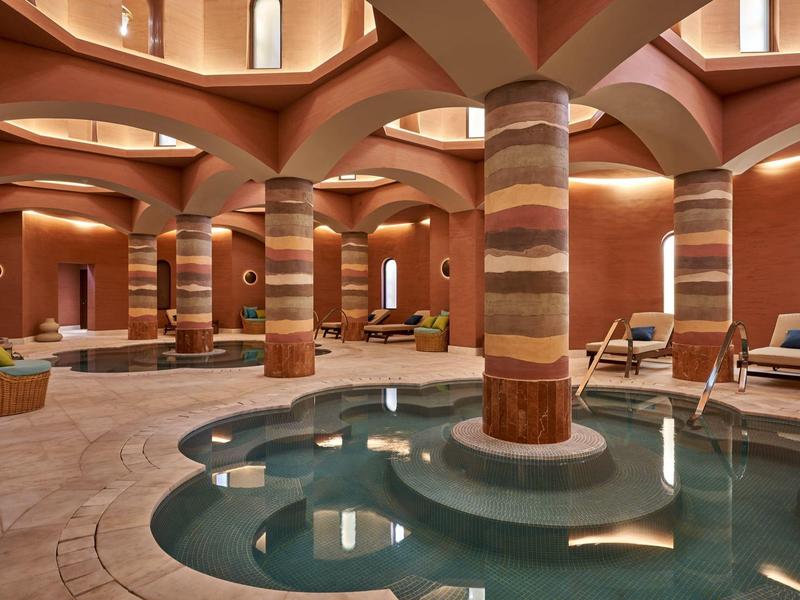 Interno lussuoso con piscina, colonne decorative e illuminazione soffusa.