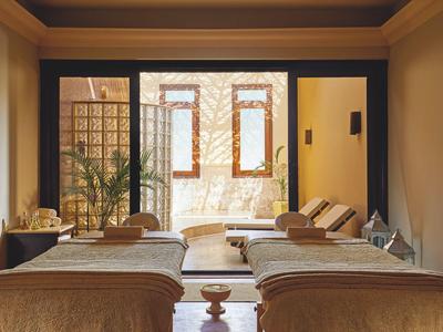 Due letti in una stanza con accesso a una terrazza soleggiata con lettini.