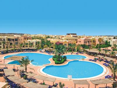 Complex hôtelier avec deux grandes piscines, des palmiers et des bâtiments de couleur terre cuite