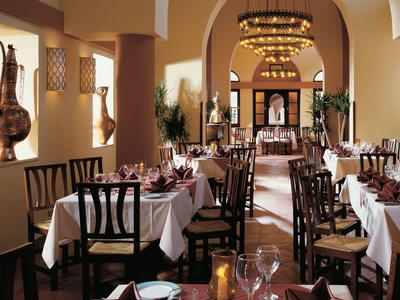 Sala da pranzo elegante con tavoli apparecchiati, sedie di legno e illuminazione calda.
