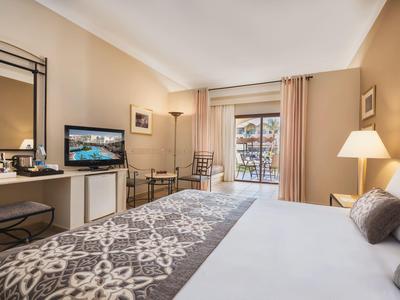 Camera d'hotel elegante con letto grande, TV, scrivania e balcone luminoso.