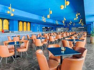 Modernes Restaurant mit orangen Stühlen und blauen Wänden in einem Hotel.