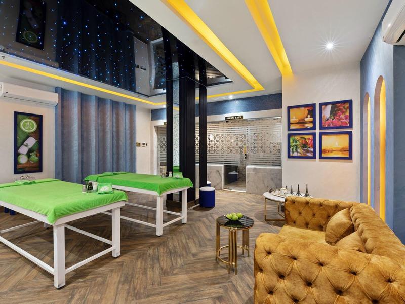 Sala ricreativa con tavoli da biliardo verdi, divano giallo ocra e design moderno.