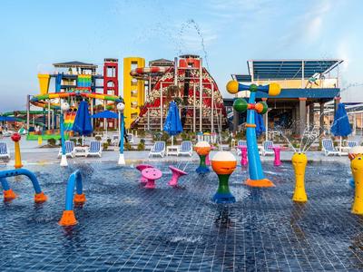 Buntes Wasserspielplatz mit Rutschen und Wasserspritzern im Hotel-Freizeitbereich.