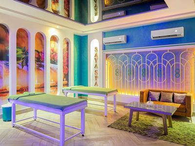 Sala de bienestar moderna con camillas de masaje, sofá y iluminación relajante.