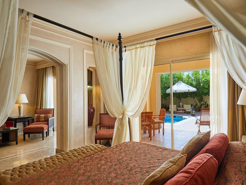 Dormitorio elegante con cama con dosel y vista a una piscina al aire libre.