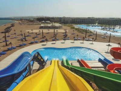 Uitzicht vanaf kleurrijke glijbanen op zwembad, parasols en resort bij de zee.