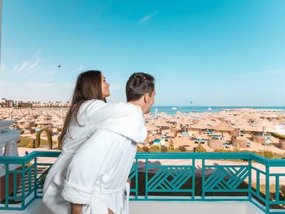 Coppia che gode di una vista soleggiata dal balcone su una città con spiaggia.