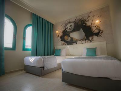 Camera d'hotel con due letti, tende turchesi e un grande murale con un panda.