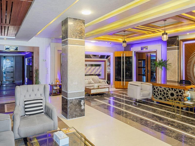 Reception d'hotel moderna con pavimento in marmo e illuminazione calda al soffitto.