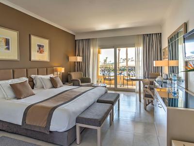 Modernes Hotelzimmer mit zwei Doppelbetten, Balkonzugang und stilvoller Einrichtung.