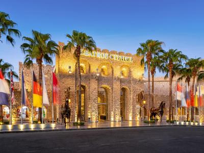 Hotel di lusso illuminato con palme e molte bandiere di notte.