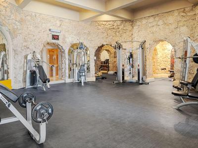 Moderne fitnessruimte met stenen structuur en verschillende fitnessapparaten.