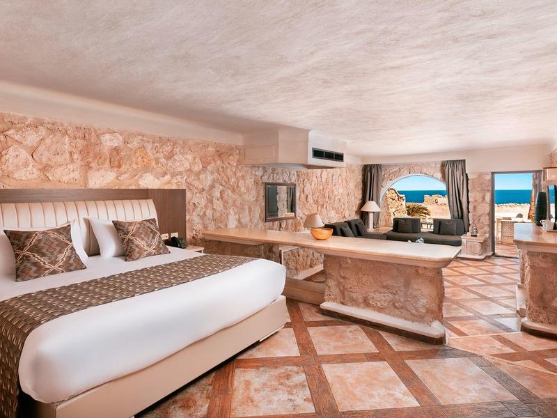 Camera d'hotel lussuosa con letto grande, pavimento in marmo e terrazza vista mare.