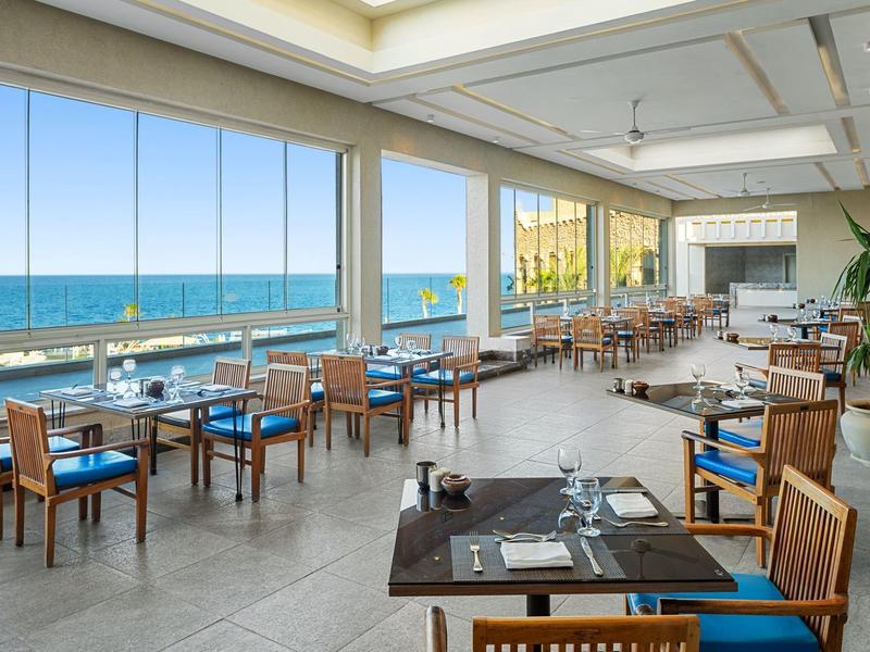 Ristorante aperto con vista mare e mobili in legno moderno alla luce del giorno.