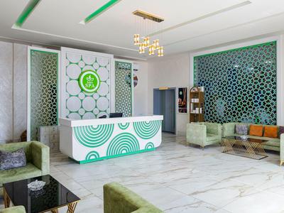 Moderní hotelová lobby se zeleno-bílou recepcí a sametovou sezením.