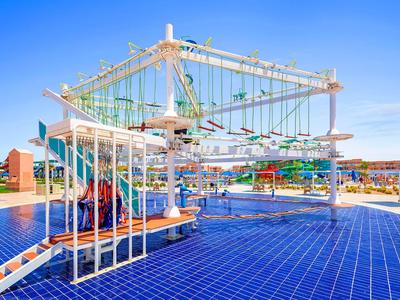 Modern climbing playground at hotel with blue floor and clear sky.