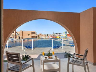 Balkón se dvěma židlemi a stolem s výhledem na marínu s loděmi pod jasnou oblohou.