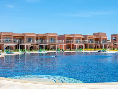 Grande piscina davanti a file di camere d'hotel moderne su due piani con cielo azzurro sullo sfondo.