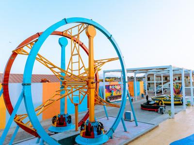 Colorful miniature roller coaster with loops in an outdoor amusement area under clear sky