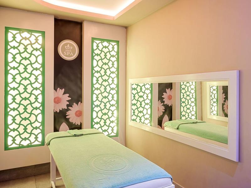 Světla spa místnost s masážním stolem a dekorativními stěnovými panely s květinovými vzory.