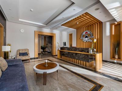 Moderní hotelová lobby s dřevěnými prvky, pohovkou a recepcí za denního světla.