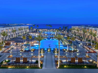 Luxuriöses Resort mit beleuchtetem Pool und Palmen bei Nacht