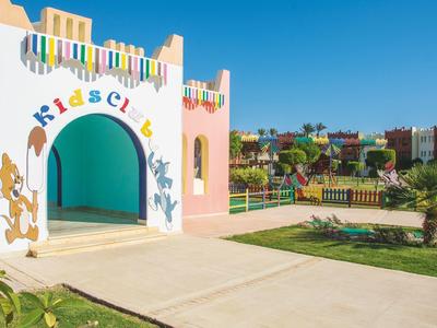 Ingresso colorato di un kids club in un resort con palme e edifici sullo sfondo.