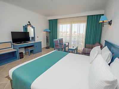 Habitación de hotel con cama doble, televisor, escritorio y balcón con vista al exterior