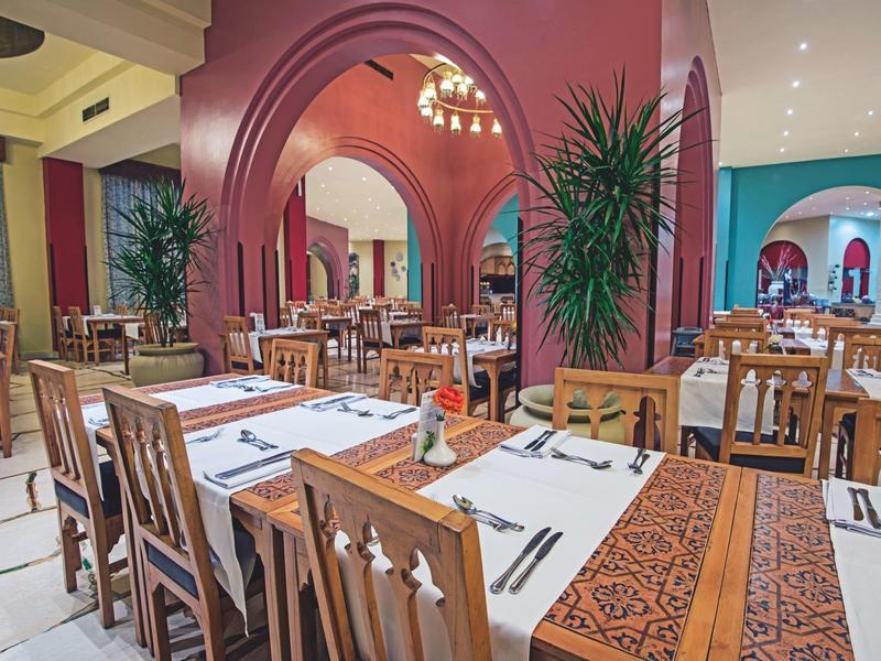 Una sala da pranzo elegante con mobili in legno, tavoli decorativi e pareti rosso-rosa.