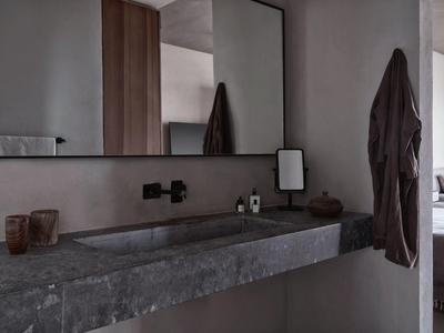 Bagno moderno con lavabo in pietra e specchio rettangolare incorniciato.