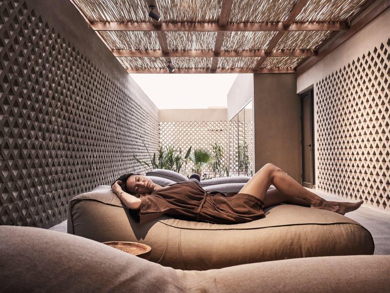 Una donna si rilassa su un divano in una terrazza privata con pareti testurizzate e luce soffusa.