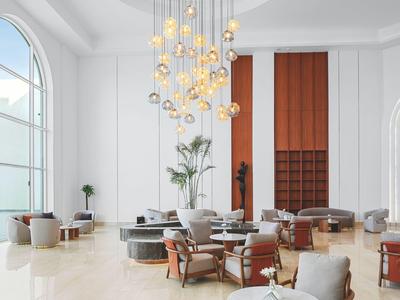 Jasna, nowoczesna lobby hotelowa z dużymi oknami i stylowymi miejscami do siedzenia.