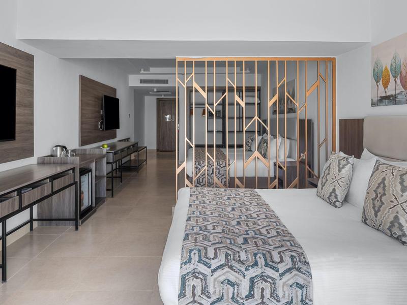 Camera d'hotel moderna con letto grande, divisorio e TV a parete.