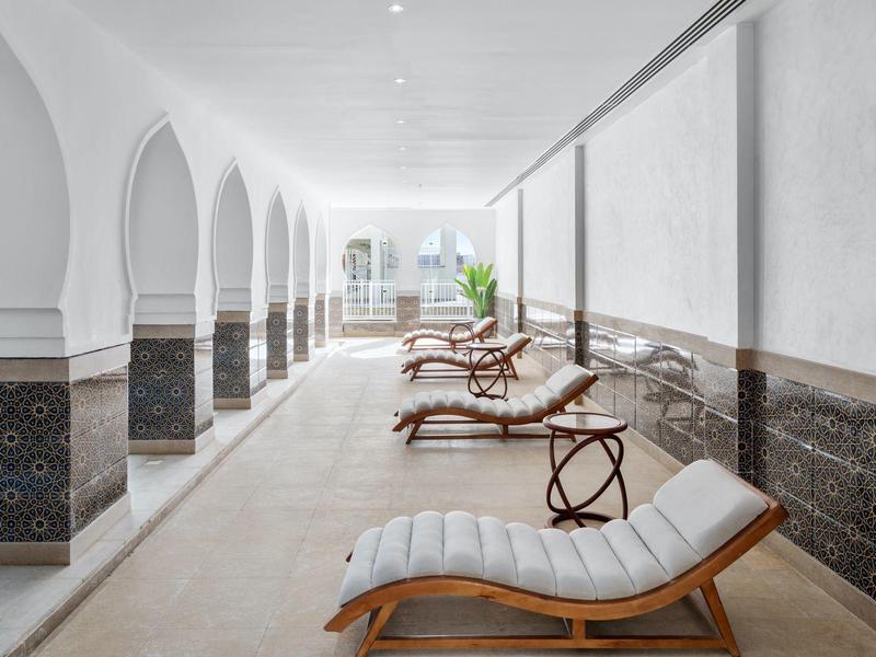 Sala benessere luminosa ed elegante con chaise longue e pareti bianche con colonne.