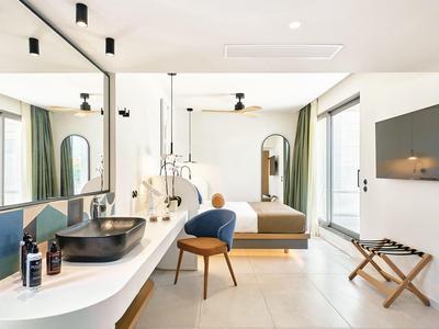 Modern hotel room with double bed, desk, chair, and large mirror.