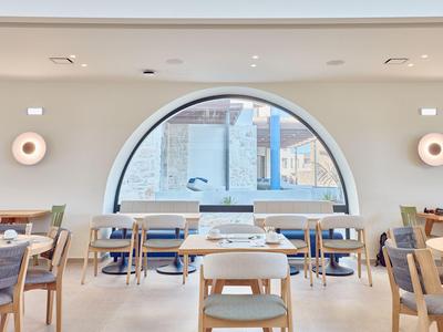 Helles, modernes Restaurant mit runden Fenstern, Holzmöbeln und gedeckten Tischen.