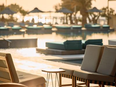 Sonnenuntergang am Pool mit Liegen und Stühlen in einem Urlaubshotel.