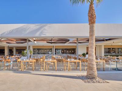 Modern hotel outdoor area with seating and pool under clear blue sky