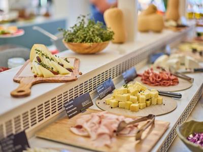Buffet with various cheeses and cold cuts at a hotel breakfast bar.