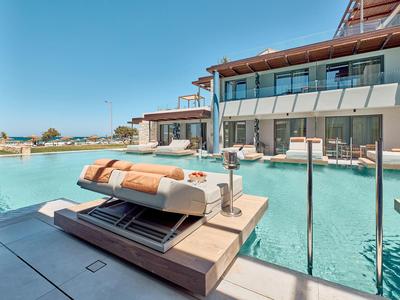 Modern hotel with pool, loungers, and terrace view under sunny skies.