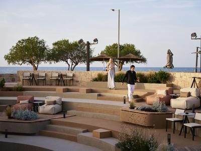 Freiluft-Amphitheater am Meer mit Sitzgelegenheiten und einer Person in sportlicher Kleidung.