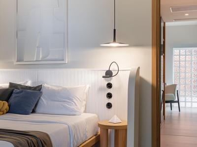Camera d'hotel moderna con letto, cuscini e lampada da comodino in tonalità soft.