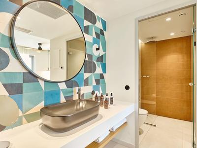 Bagno moderno con specchio rotondo, piastrelle geometriche e sanitari beige.