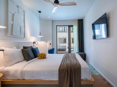 Camera d'hotel moderna con letto grande, TV e balcone con vista.